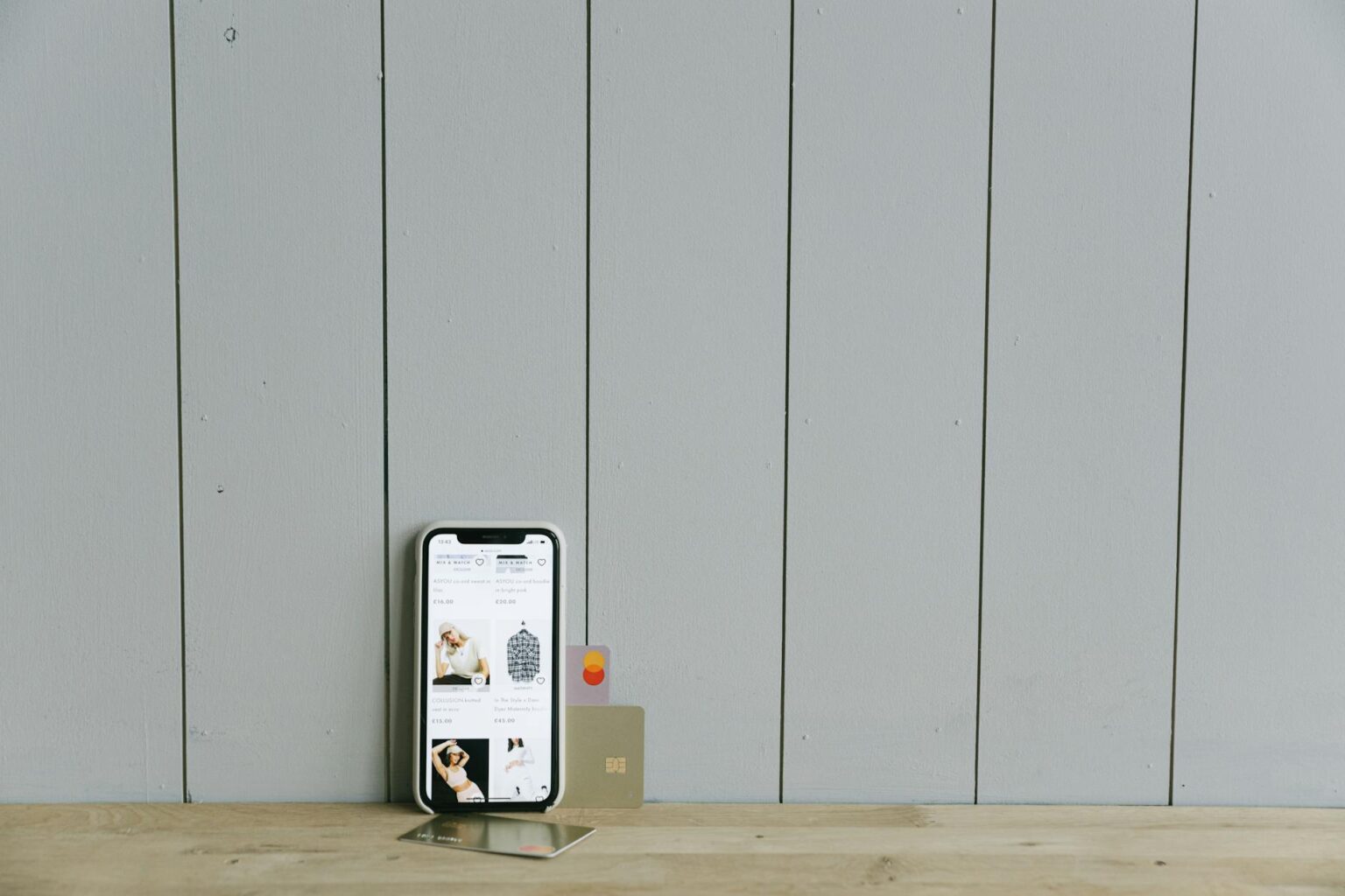 Person holding smartphone showing shopping app interface with product listings and purchase options