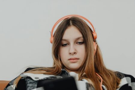 Person wearing headphones while using smartphone, representing voice message communication