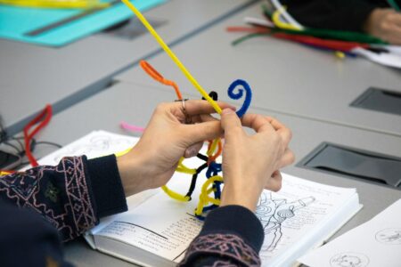 Underground Bookbinding Classes Are Reviving Ancient Craftsmanship Among Gen Z Close-up of hands working on bookbinding, stitching pages together with thread