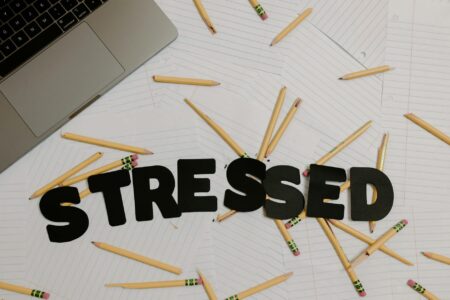 Why Workplace Wellness Programs Are Just Corporate Guilt-Washing Employee Burnout Stressed office worker at computer with head in hands surrounded by paperwork