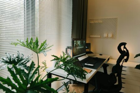 Cluttered home office desk with multiple monitors and scattered supplies