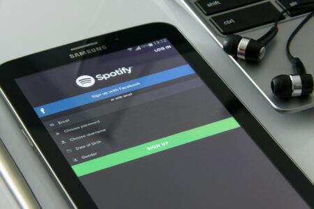 Person holding smartphone displaying colorful music streaming app interface with headphones nearby