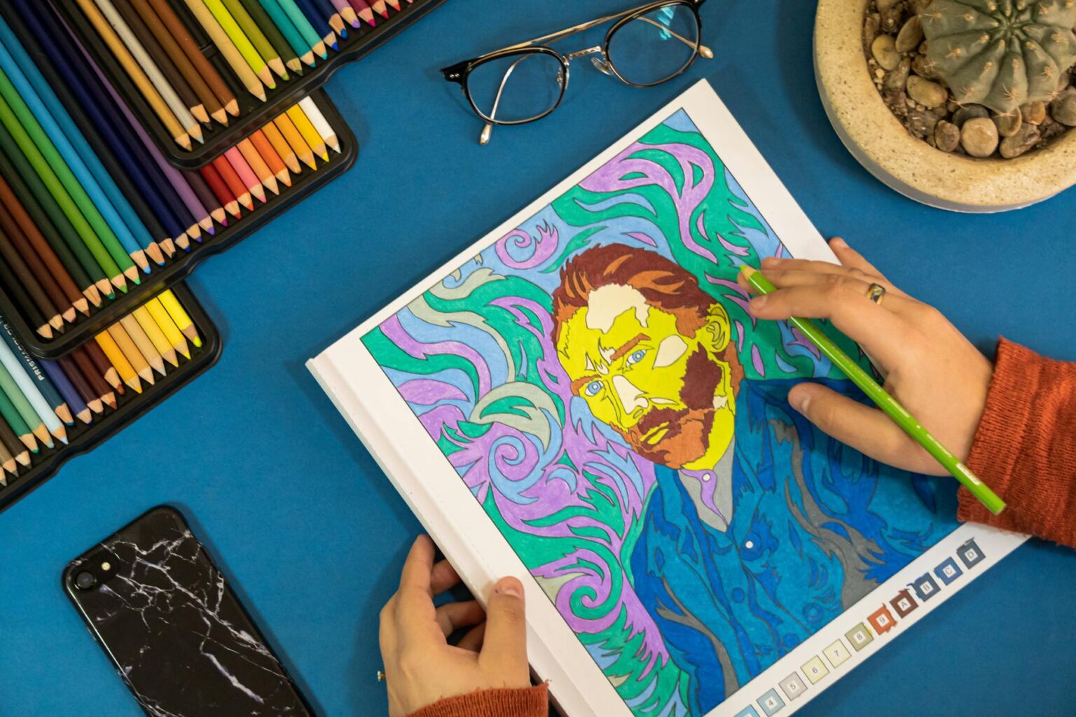 Colorful pencils arranged next to an open adult coloring book showing intricate mandala patterns