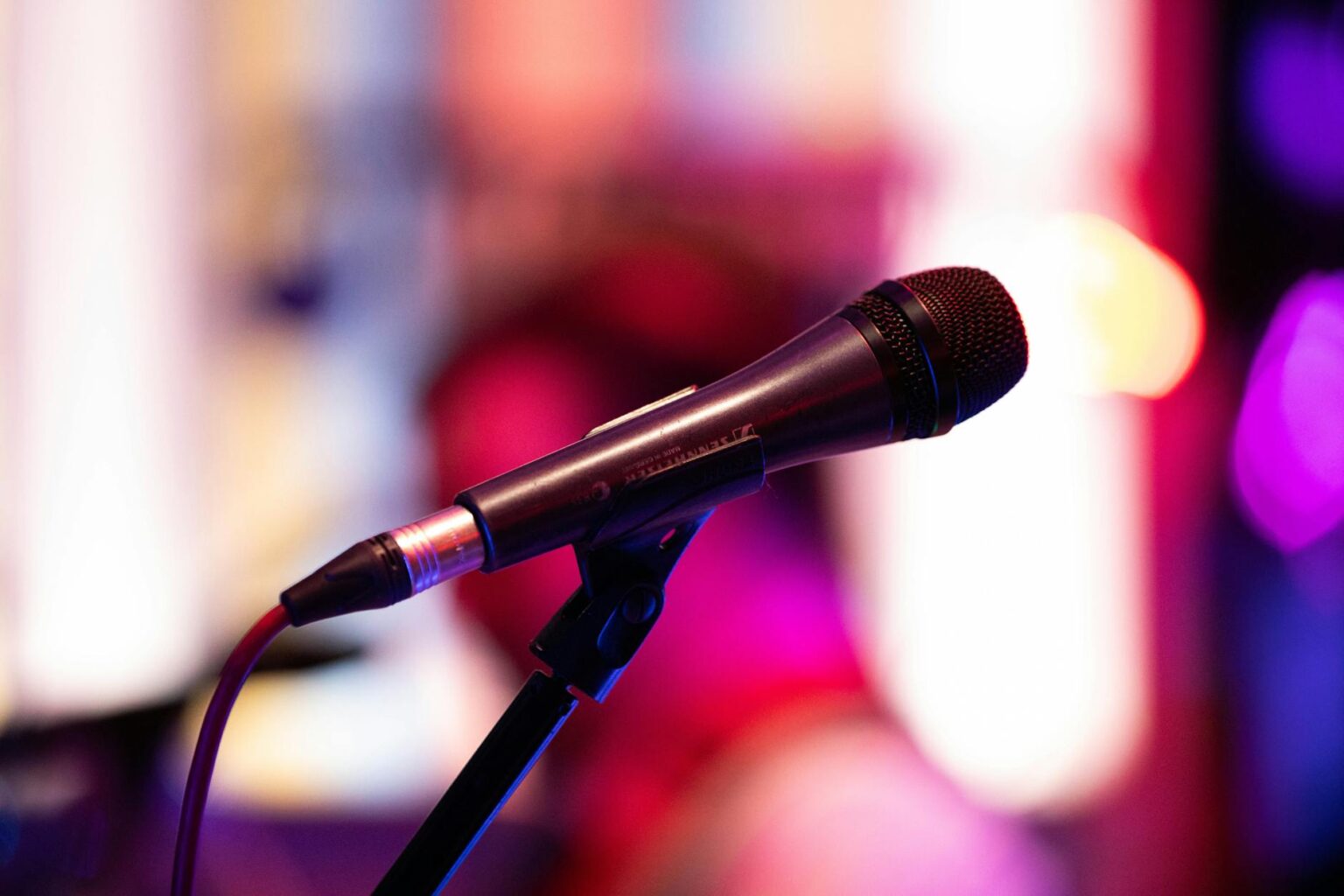 Stand-up comedian performing with microphone on stage under spotlight