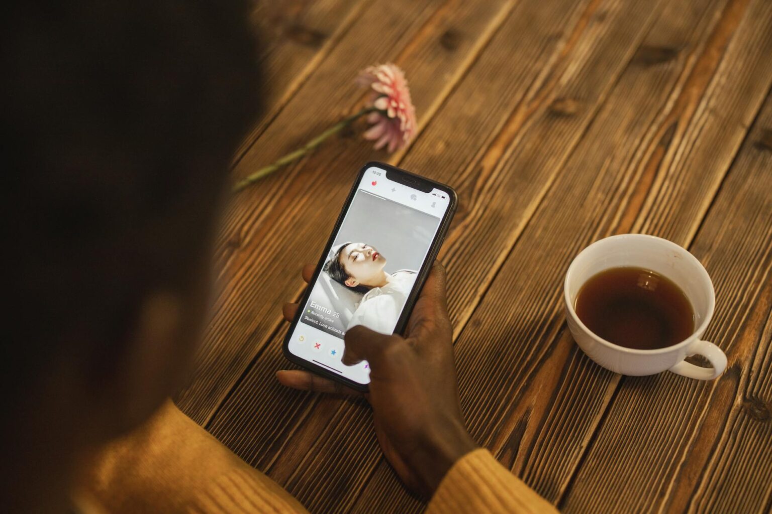 Person holding smartphone with dating app interface visible on screen