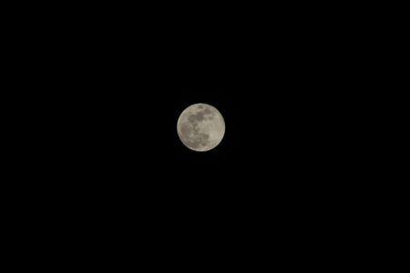 Bright full moon illuminating dark night sky