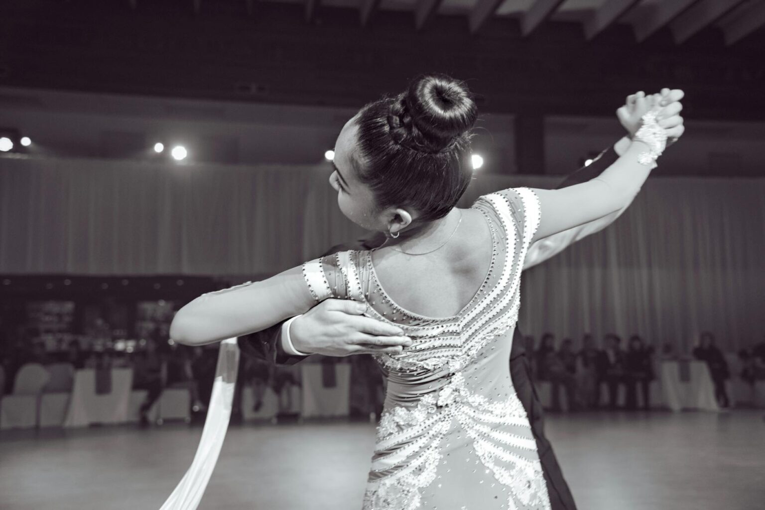 Professional ballroom dancers performing elegant routine on polished dance floor