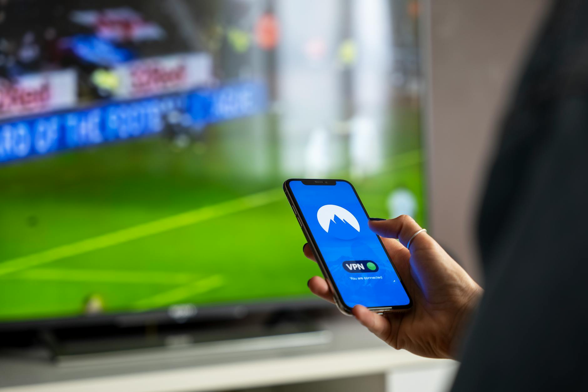 Person holding a remote control in front of a television screen
