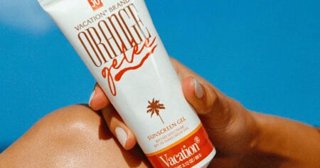 This Is The Glowiest Body Sunscreen I’ve Tried – & It’s On Sale Person applying sunscreen lotion to their arm outdoors