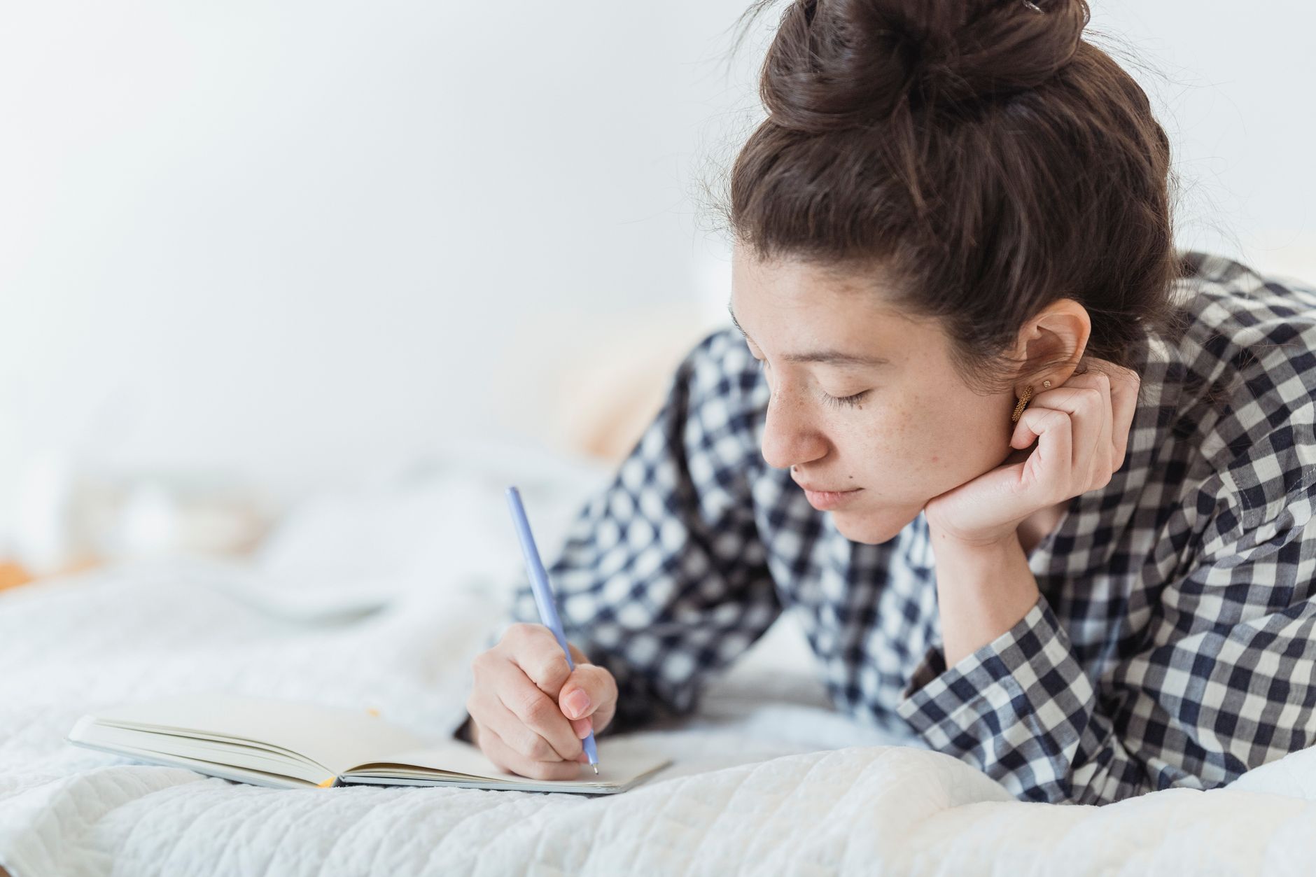 A woman writing in a journal during a quiet morning, reflecting on personal goals