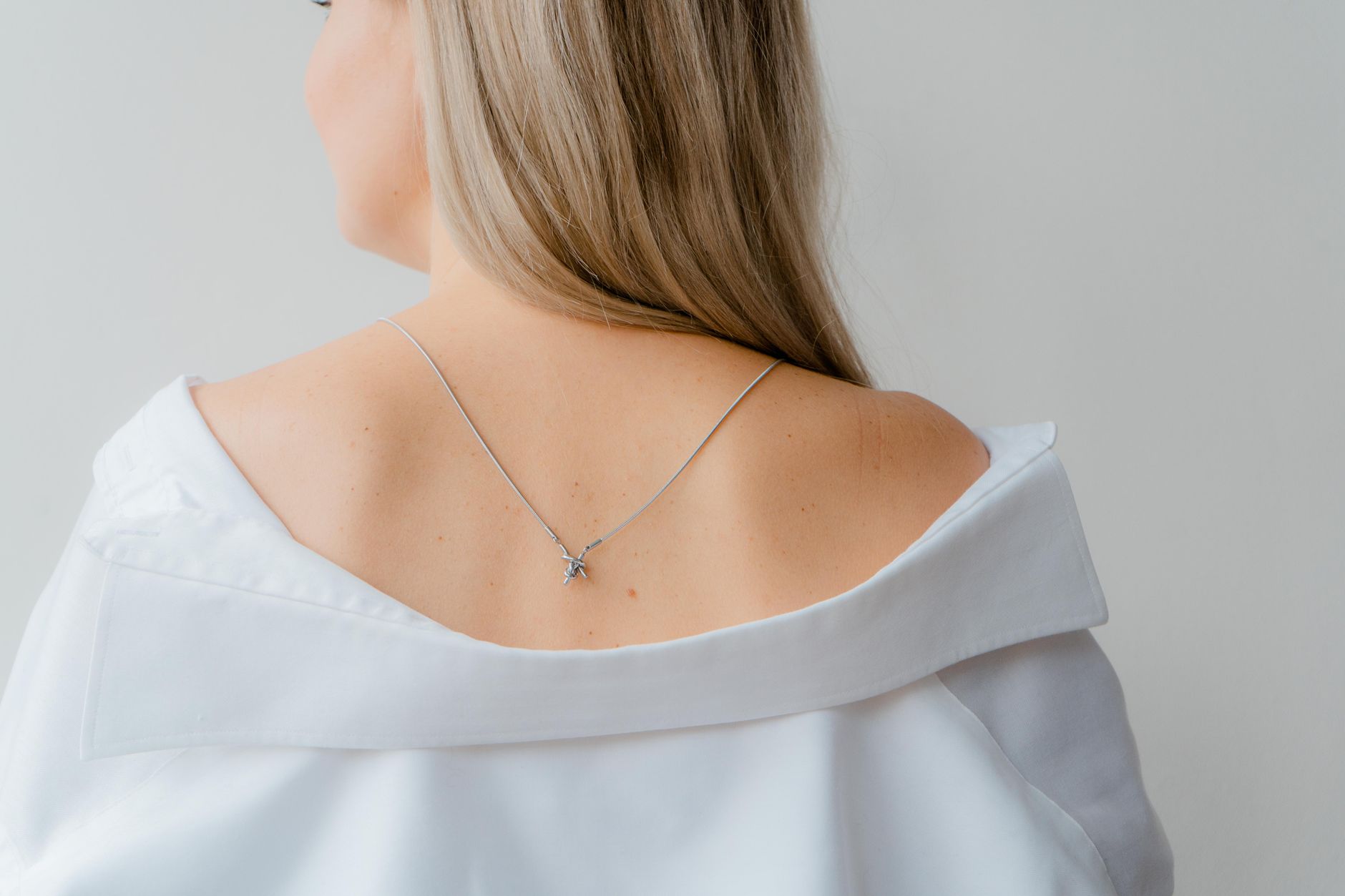 Woman wearing a chain link necklace with a simple white t-shirt in natural light