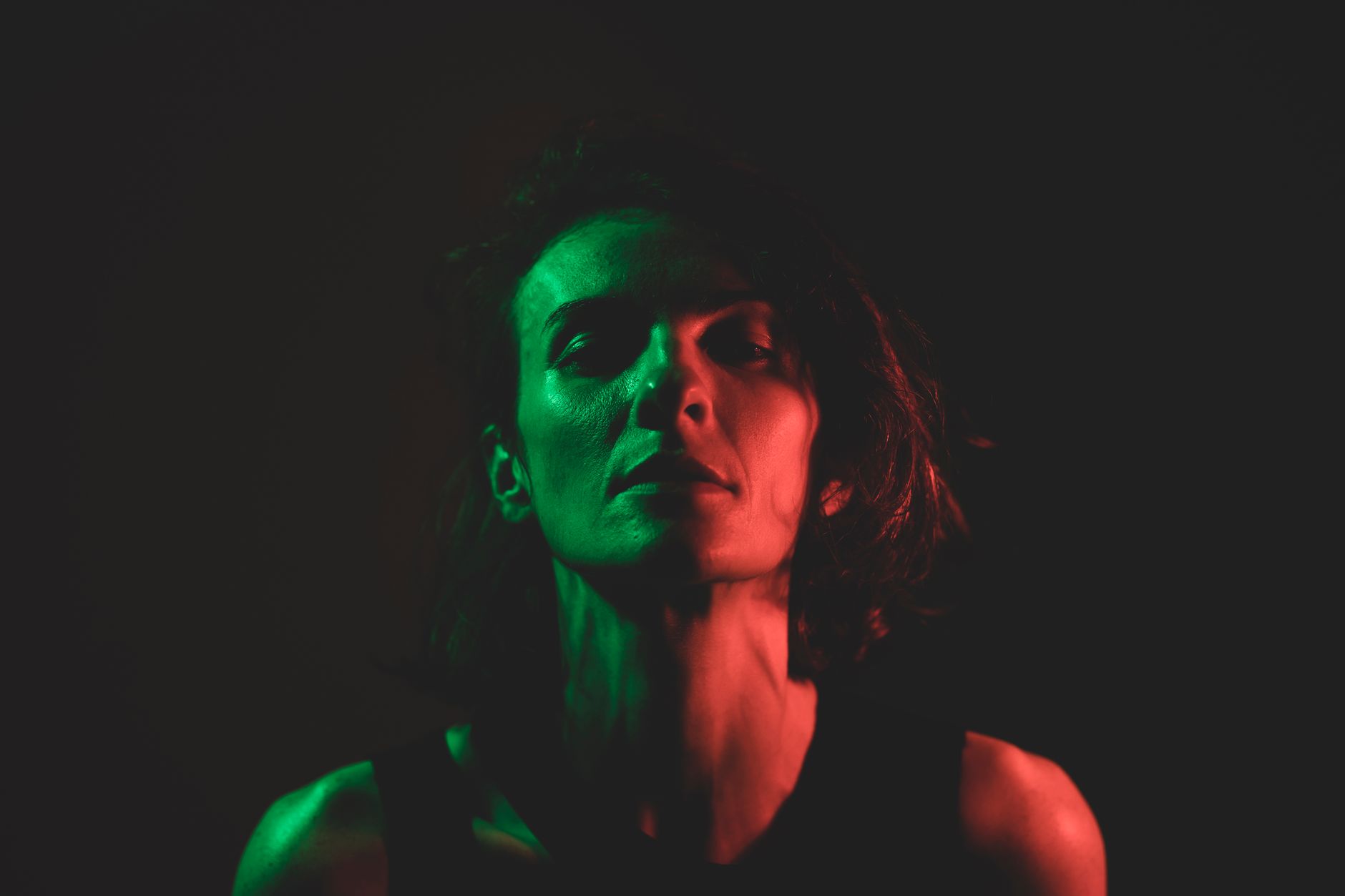 A woman with a composed, determined expression in dramatic lighting