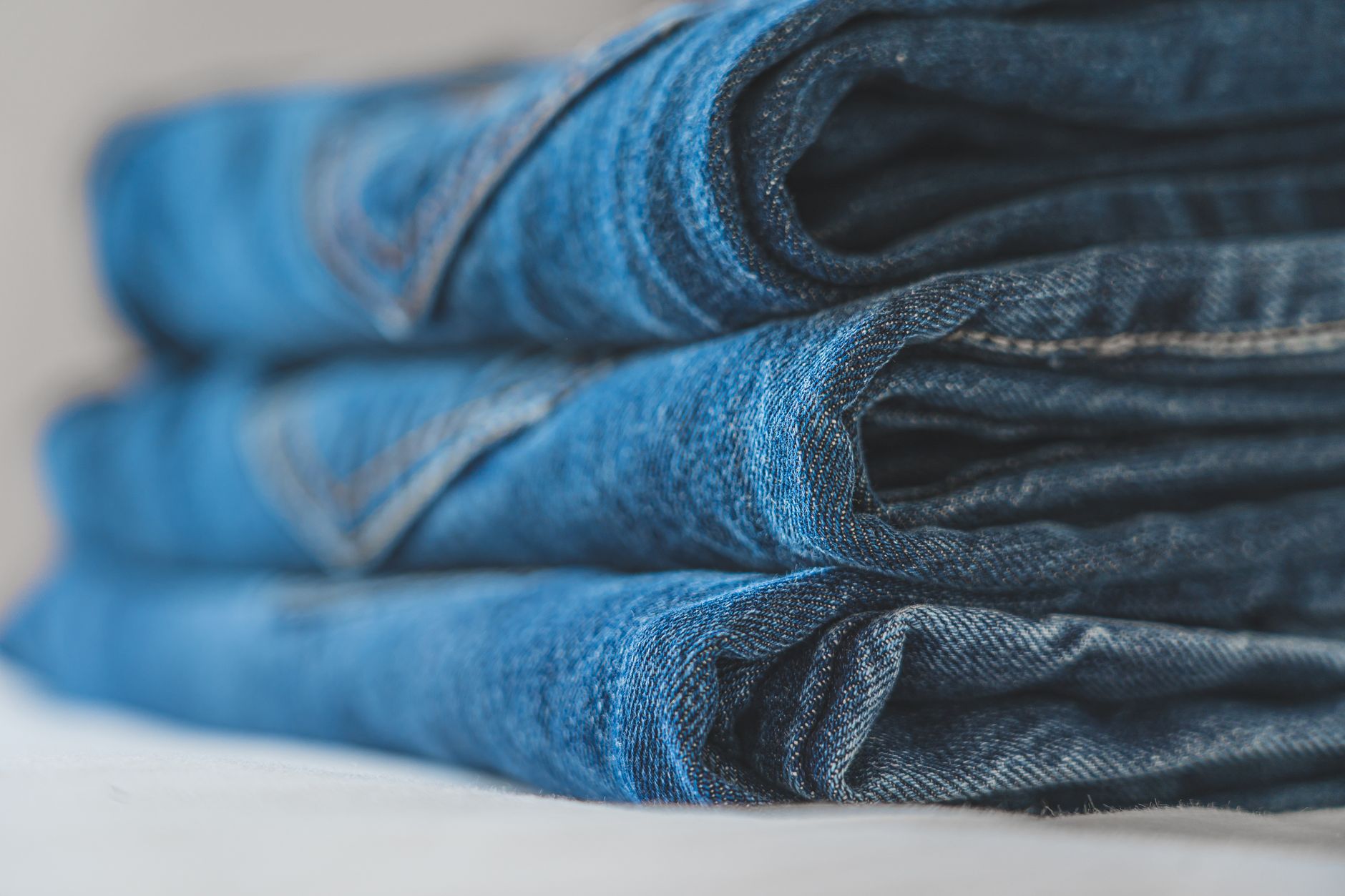 Neatly folded pants and travel clothing laid out on a bed before packing into a suitcase