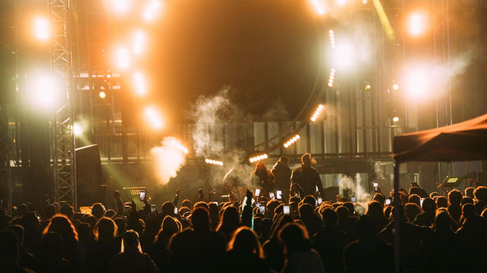 Artist performing under bright stage lights before a large arena crowd