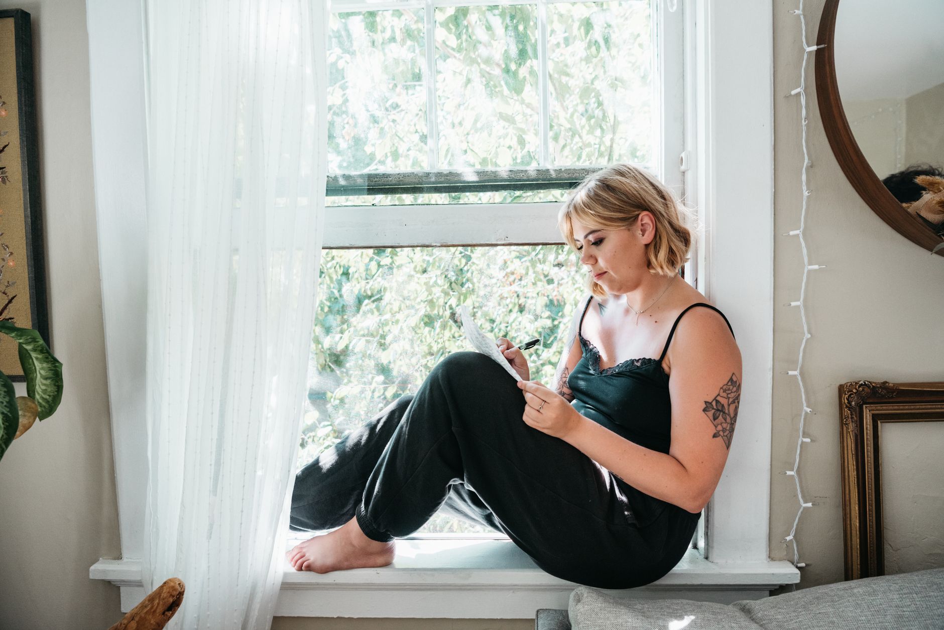 Woman writing in a journal by a window with soft natural light