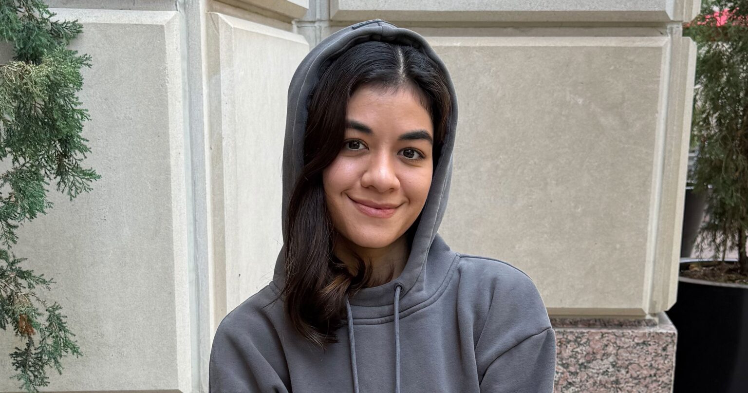 The Hoodie With a Built-In Eye Mask That Won February Person wearing a grey hoodie in a relaxed travel setting