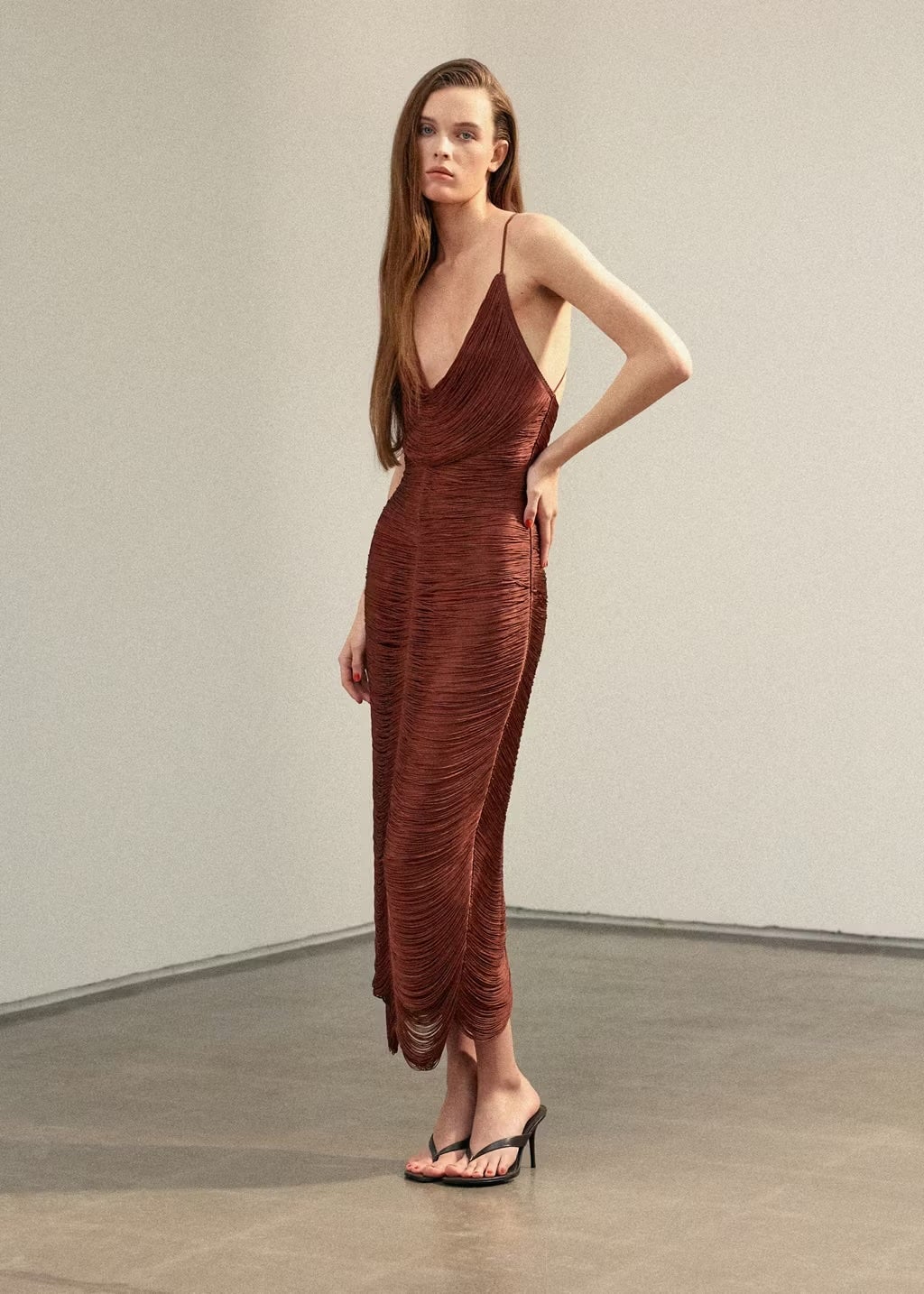 Close-up of fringe sash accessory styled as a belt over a silk dress