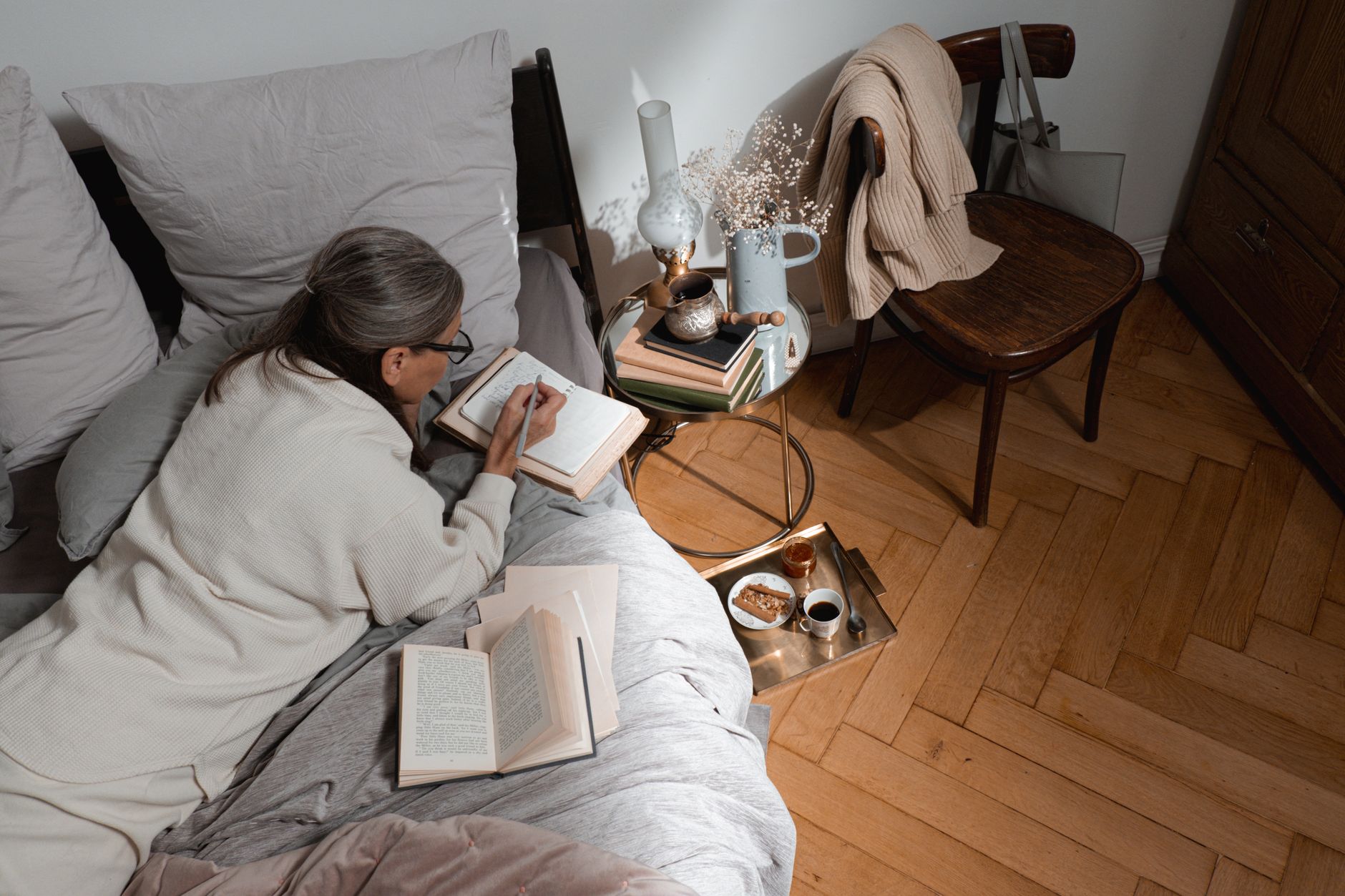 Woman writing in a journal at a wooden desk in soft morning light