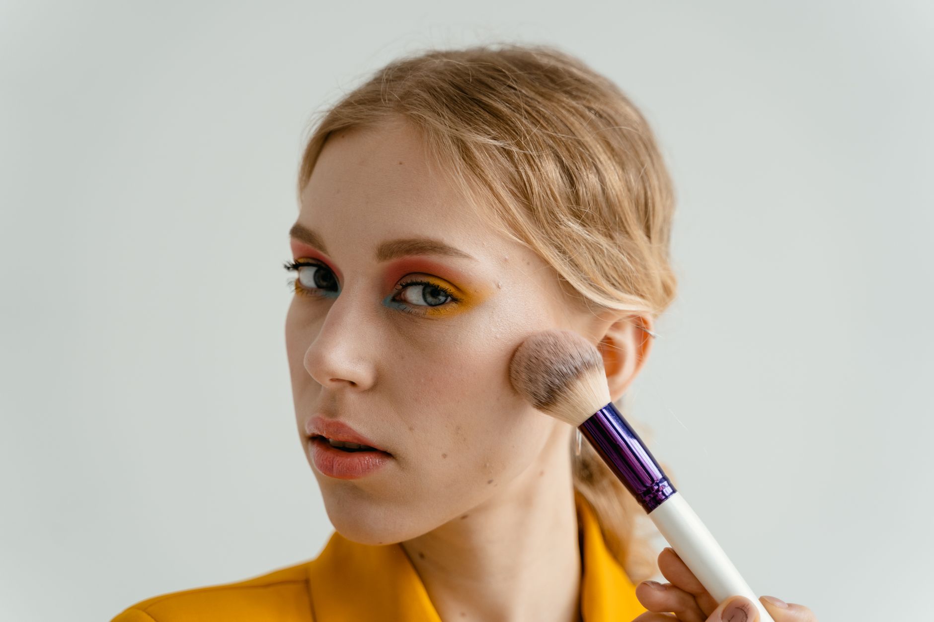 Woman blending blush onto her cheeks using fingertips in natural light